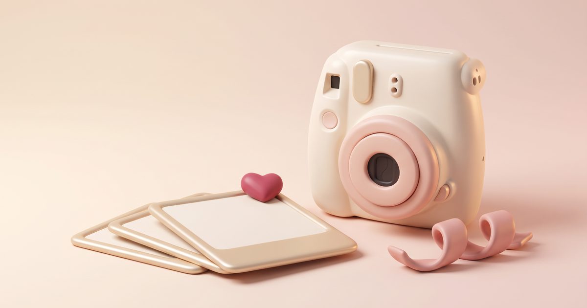 A cream camera beside three blank photo prints and a small rose heart