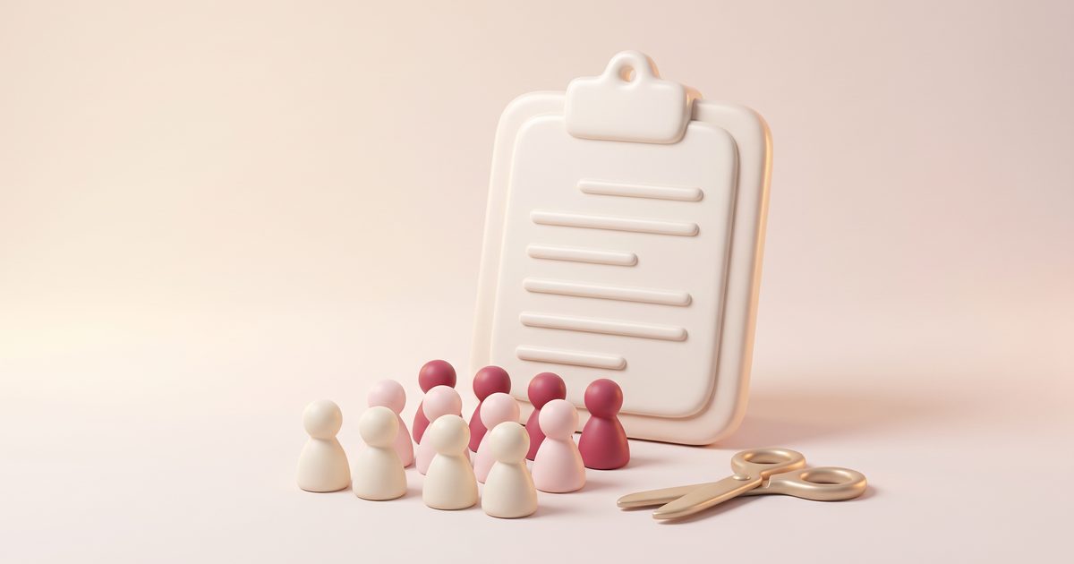 A cream clipboard with rows of small clay figures and gold scissors in front of it