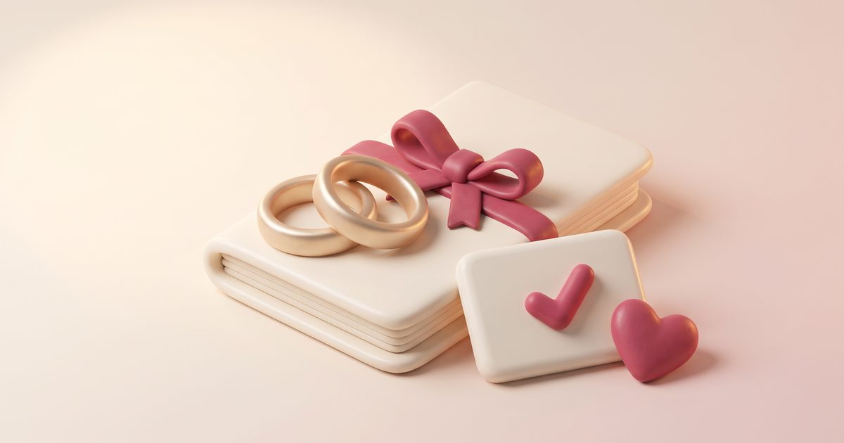 Two gold wedding rings resting on a cream planning notebook tied with a rose ribbon