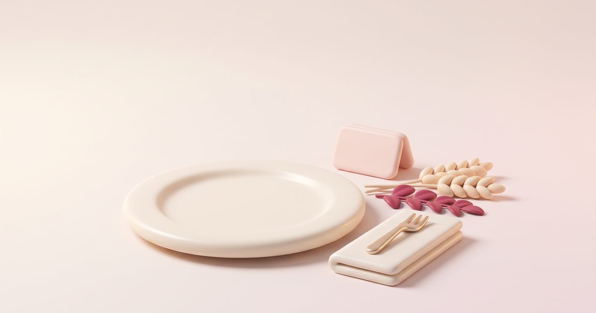 A cream dinner plate with a blush place card beside it, a sprig of wheat and rose leaves, and a small gold fork on a folded cream napkin