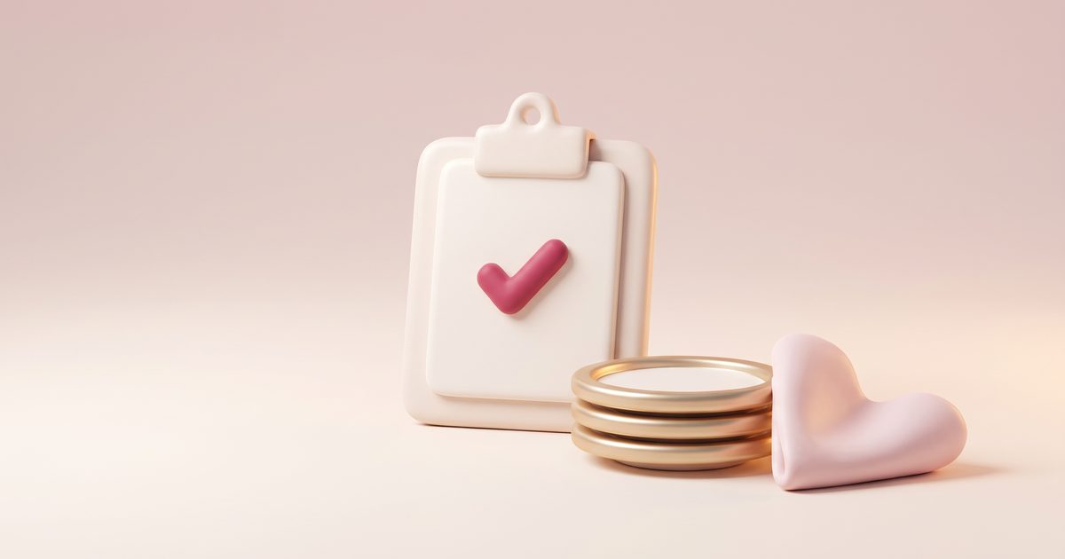 A cream clipboard with a rose tick beside a small stack of gold-rimmed plates and a blush heart