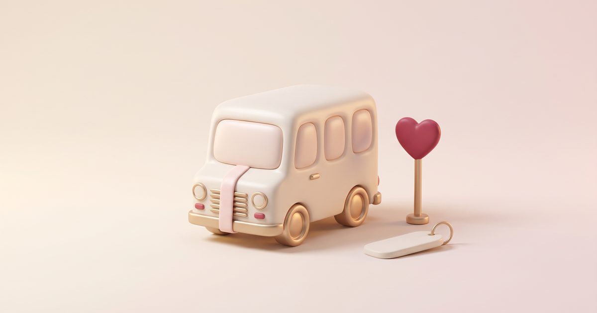 A cream clay shuttle bus with gold wheels and a blush ribbon beside a rose heart sign and a key tag