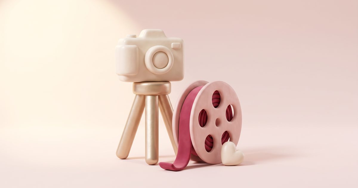 A cream film camera on a gold tripod beside a blush film reel threaded with a rose ribbon